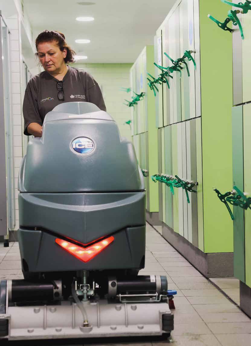 A member of the cleaning team operating a scrubber-dryer machine in a changing room