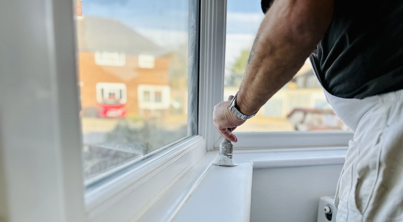 A Lampton tradesperson painting a window sill in a Hounslow home
